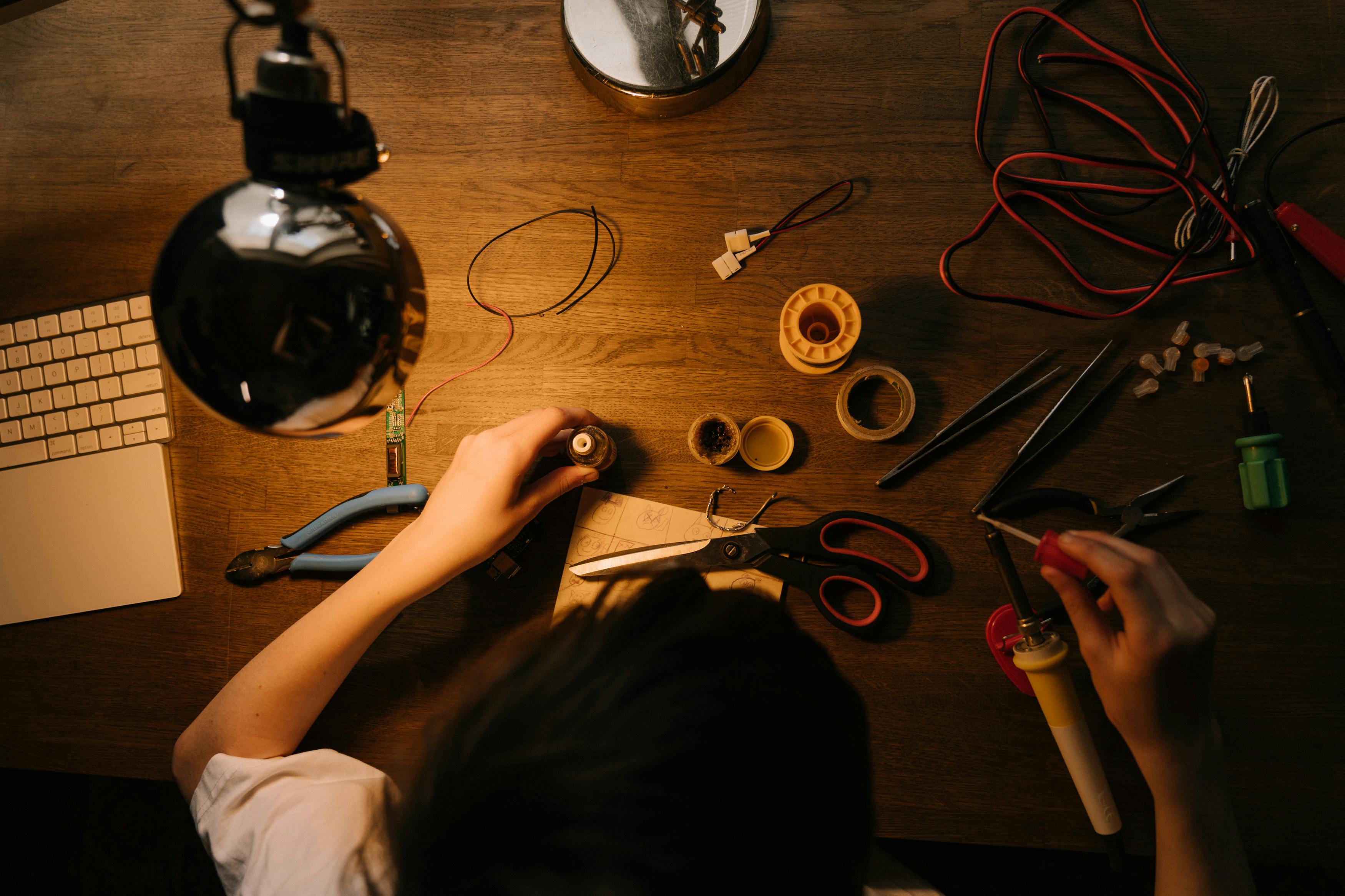 Person working on electronics repair with soldering tools at a desk.